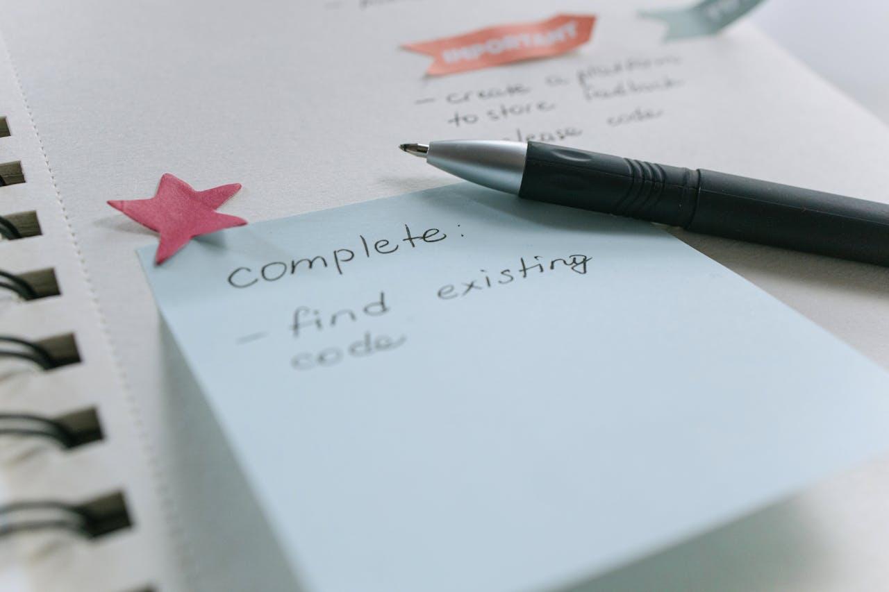 A notebook with a sticky note and pen on it.